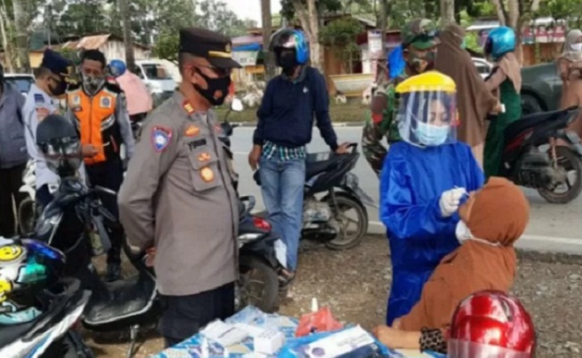 Perwira Pengendali Operasi Tim Yustisi Kendari AKP Yusuf Muluk saat memantau seorang pengendara dilakukan uji usap antigen karena suhu tubuhnya di atas 37 derajat celcius,