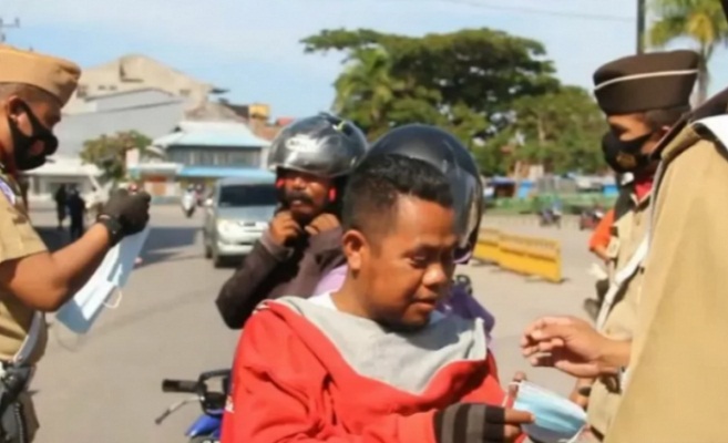 Ilustrasi - Anggota Kepolisian Satuan Lalu Lintas Polres Baubau di Sulawesi Tenggara saat membagikan masker kepada pengendara yang tidak menggunakan masker,